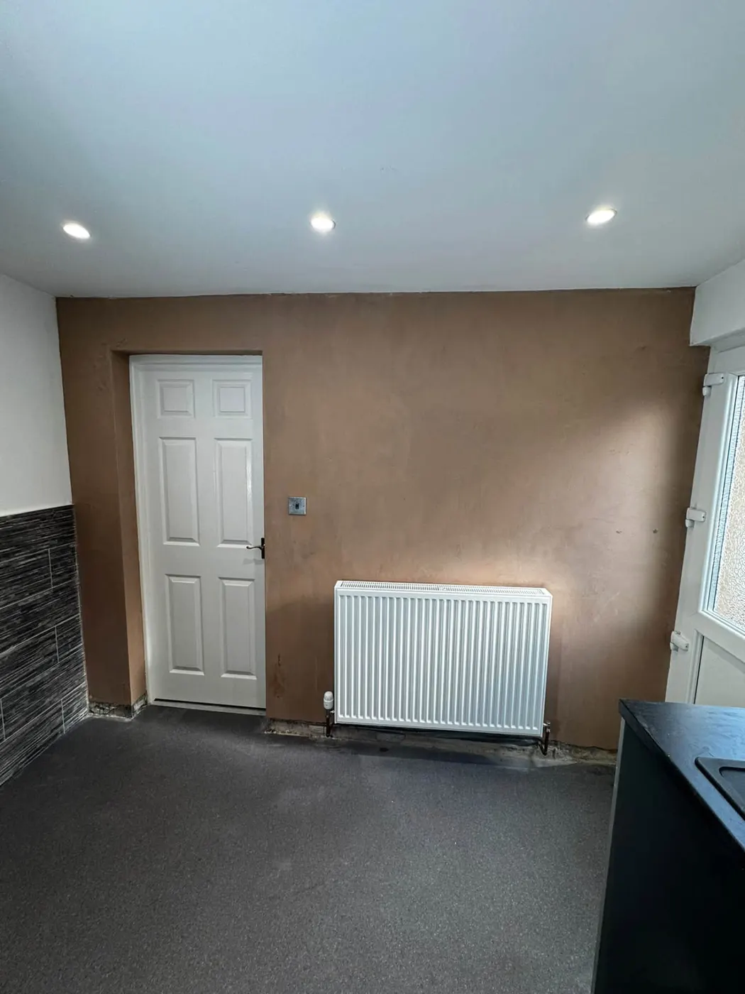 Freshly plastered smooth internal wall around a door and radiator, Carlisle