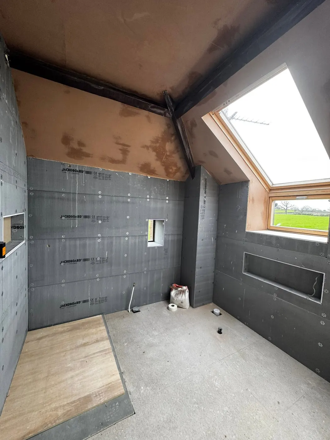 Bathroom walls boarded during preparation work, with skylight